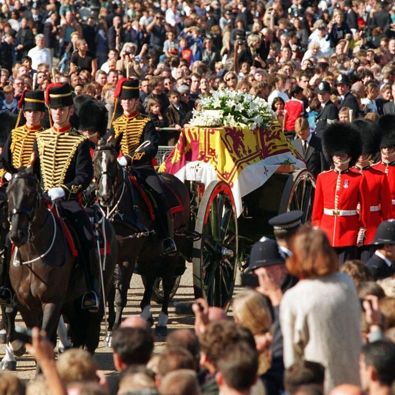 Begleitet von der Königlichen Garde wird die Geschützlafette mit Prinzessin Dianas Sarg am 6. September 1997 durch die Londoner Innenstadt zur Westminster Abbey gezogen. Etwa zwei Millionen säumen den Trauerzug der verunglückten Prinzessin von Wales.