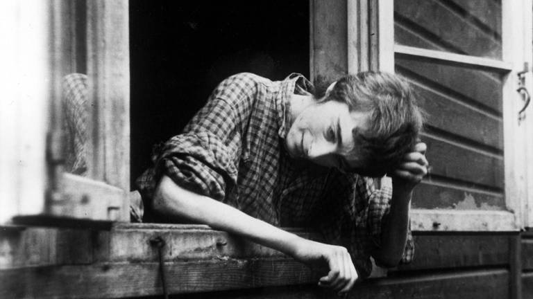 Überlebende Frau schaut in Bergen-Belsen aus dem Fenster einer Baracke, nachdem das Konzentrationslager am 15. April 1945 durch britische Truppen befreit worden war. Die Soldaten fanden Tausende unbestattete Leichen und Zehntausende todkranke Menschen vor, die an Typhus, Ruhr und anderen Krankheiten litten.