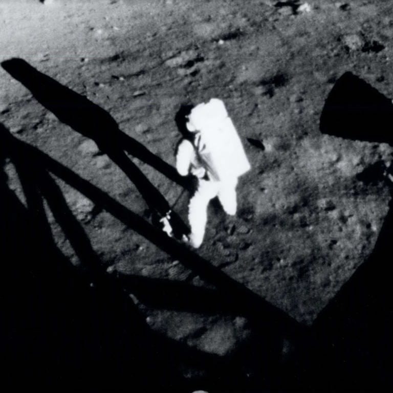 Der Kommandant von Apollo 11, Neil Armstrong, sammelt Proben des Mondbodens, kurz nachdem er am 20. Juli 1969 seinen historischen ersten Schritt auf der Oberfläche des Mondes gemacht hat. Das Foto wurde von Edwin "Buzz" Aldrin aus dem Inneren des Landefahrzeugs aufgenommen. Im Vordergrund ist ein Teil des Fahrzeugschattens sichtbar.