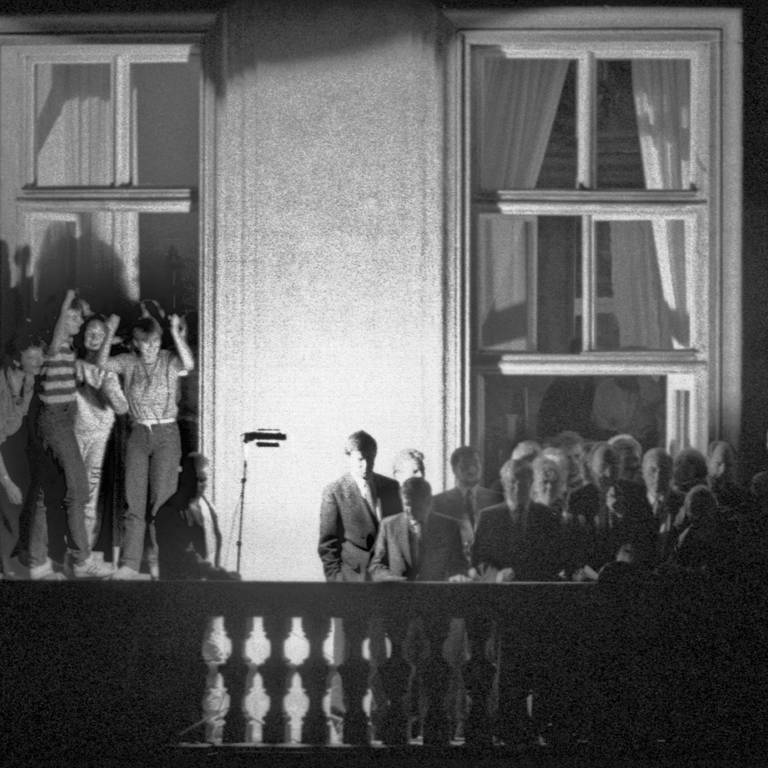 Der damalige Außenminister Hans-Dietrich Genscher (unter dem Fensterkreuz rechts) mit anderen Politikern auf dem Balkon der bundesdeutschen Botschaft in Prag. Am 30. September 1989 hatte der FDP-Politiker dort den DDR-Bürgern im Garten verkündet, dass ihre Ausreise möglich geworden war. (Foto: dpa Bildfunk, picture alliance / dpa | Reinhard Kemmether)