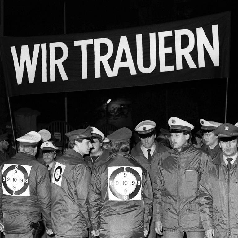Mit einem schwarzen Transparent und der Aufschrift "Wir trauern" demonstrieren Polizisten während eines Trauermarsches durch die Frankfurter Innenstadt am 4. November 1987. Sie zeigen ihre Bestürzung über den Tod der am 2. November während einer Demonstration an der Startbahn West des Frankfurter Flughafens erschossenen zwei Kollegen.