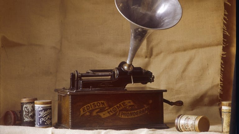 Ein früher Edison-Phonograph mit gerillten Wachszylindern neben dem Instrument; Anfang 20. Jahrhundert