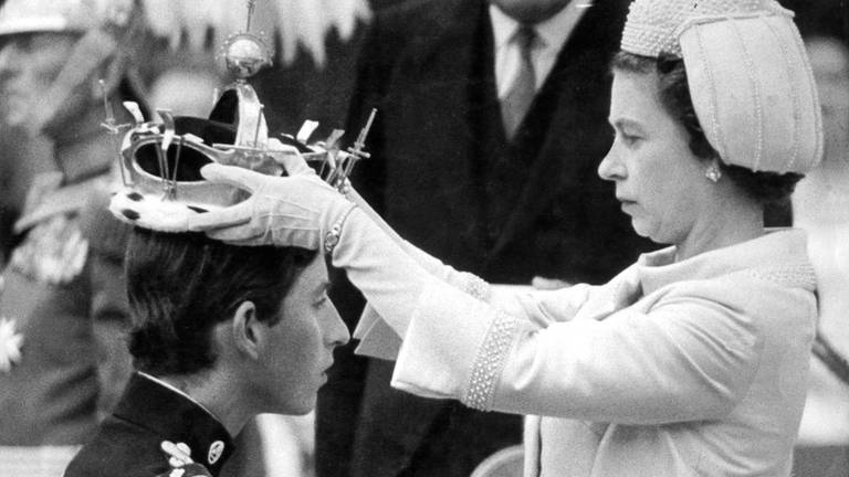 Charles kniet bei seiner Invesitur zum Prince of Wales am 1. Juli 1969 vor seiner Mutter, Elizabeth II, als die Queen im die juwelenbesetzte Goldkrone in Caernarfon Castle auf den Kopf setzt
