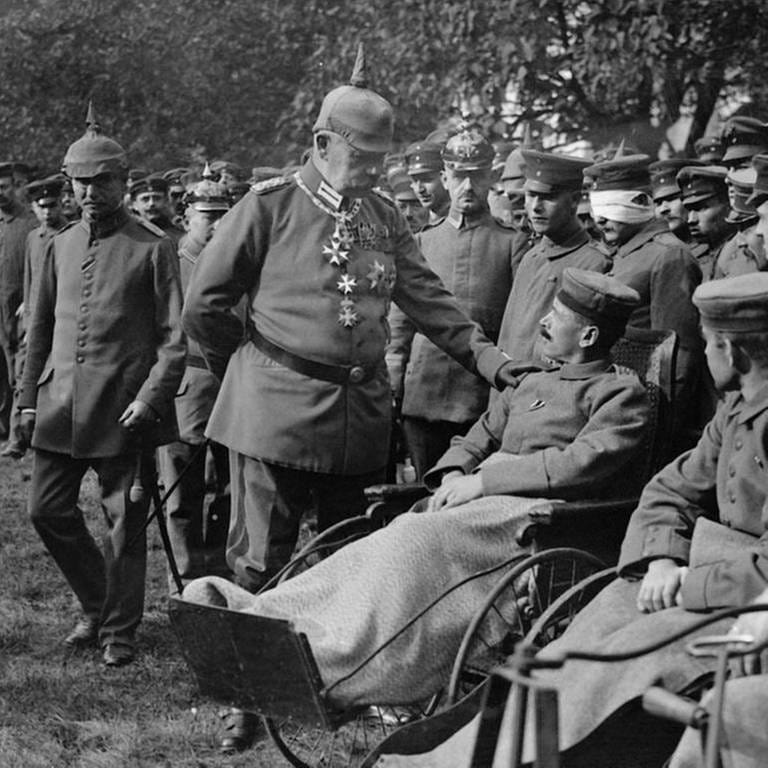 Paul von Hindenburg besucht Verwundete des Ersten Weltkrieges, Soldaten in Reihe aufgestellt, im Vordergrund in Rollstühlen (Foto: IMAGO, IMAGO / Arkivi)
