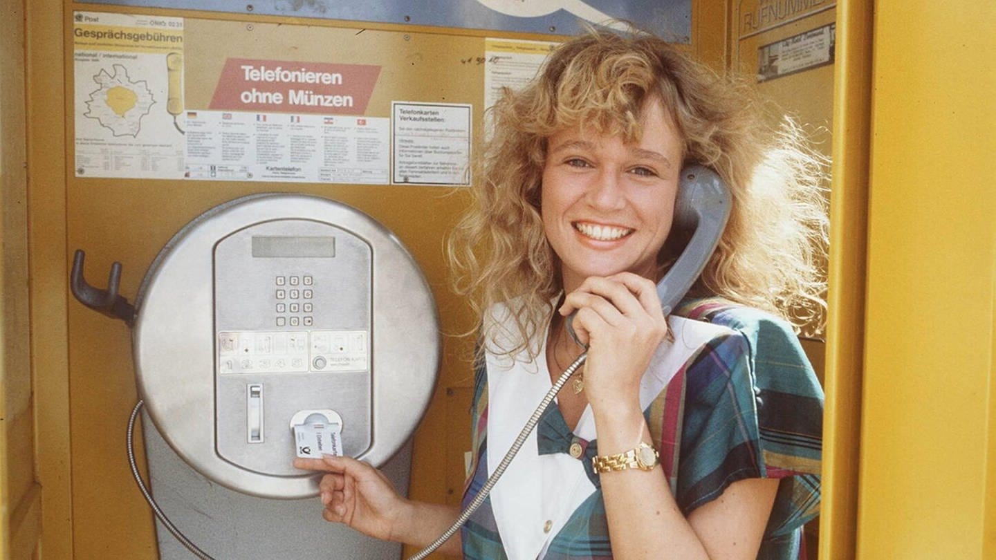 Eine Frau telefoniert in einer Tezefonzelle mit einer Telefonkarte: Das Kartentelefon galt 1987 als technische Revolution, ermöglichte es doch das Telefonieren ohne Münzen (Foto: IMAGO, IMAGO / teutopress)
