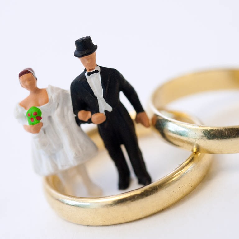 Figur eines Brautpaars in einem von zwei goldenen Eheringen:  (Foto: picture-alliance / Reportdienste, picture alliance / dpa Themendienst | Andrea Warnecke)