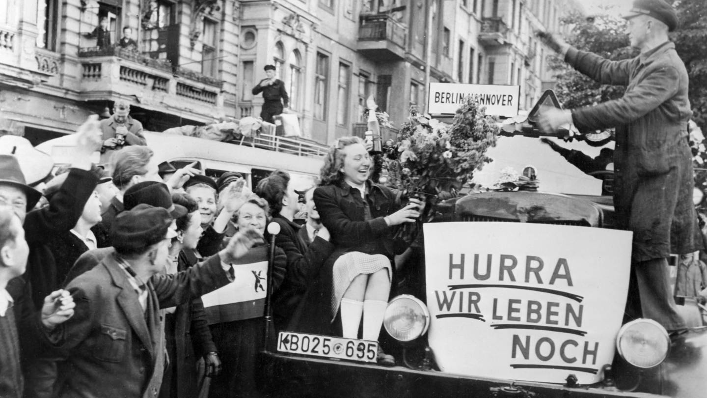 Unter dem Jubel von Bürger*innn verlassen am frühen Morgen des 12. Mai 1949 die ersten Busse Berlin in Richtung Westdeutschland (Foto: dpa Bildfunk, picture-alliance/ dpa | UPI)