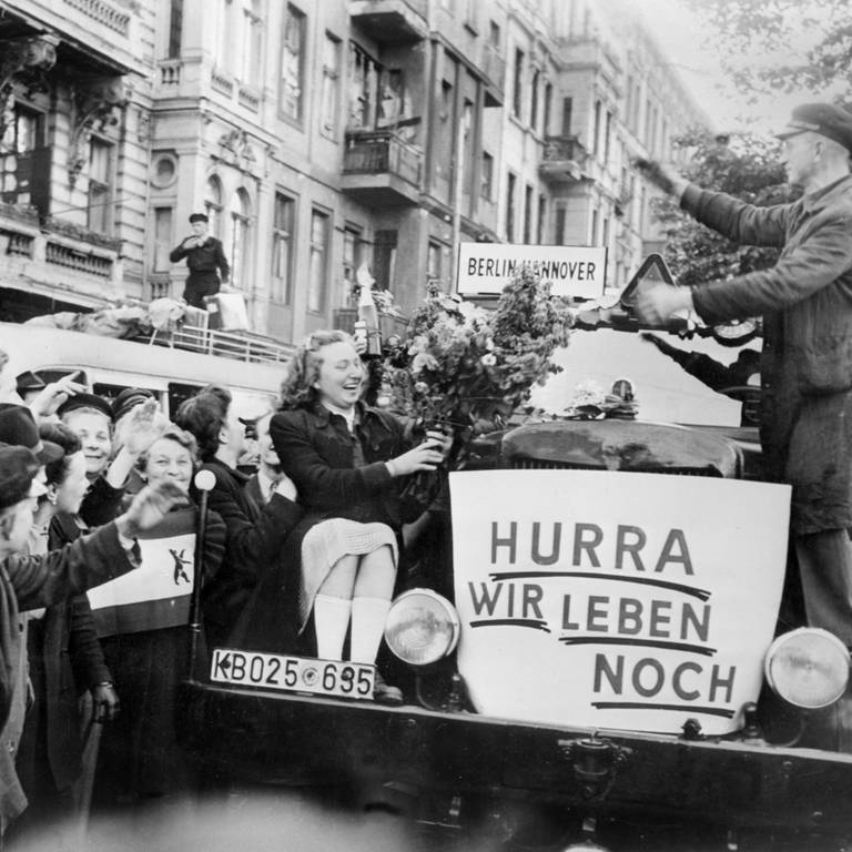 Unter dem Jubel von Bürger*innn verlassen am frühen Morgen des 12. Mai 1949 die ersten Busse Berlin in Richtung Westdeutschland (Foto: dpa Bildfunk, picture-alliance/ dpa | UPI)