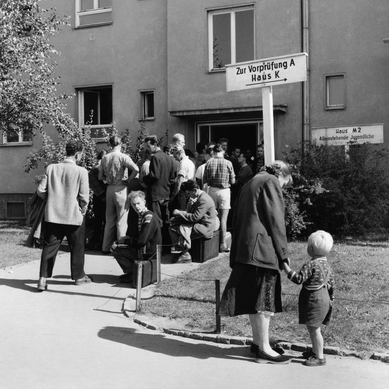 Schlange im Notaufnahmelager Marienfelde am 1. September 1958 in West-Berlin. Das Aufnahmelager für Flüchtlinge aus der DDR und Ost-Berlin war 1952  1953 erbaut worden. Ende August 1958 erreichten die Flüchtlingszahlen mit 3.000 Menschen innerhalb von drei Tagen eine neue Rekordhöhe: Blick auf die Reihe von Menschen, die im Notaufnahmelager Marienfelde auf ihre Registrierung warten.