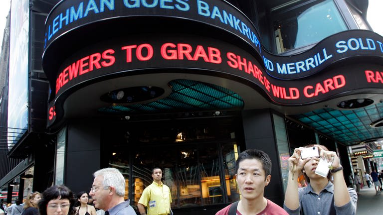 Touristen machen am 15. September 2008 Fotos auf dem New Yorker Times Square, während die Finanznachrichten des Tages im ABC-Newsticker angezeigt werden: Lehman goes bankrupt (Foto: picture-alliance / Reportdienste, picture alliance / ASSOCIATED PRESS | Mary Altaffer)