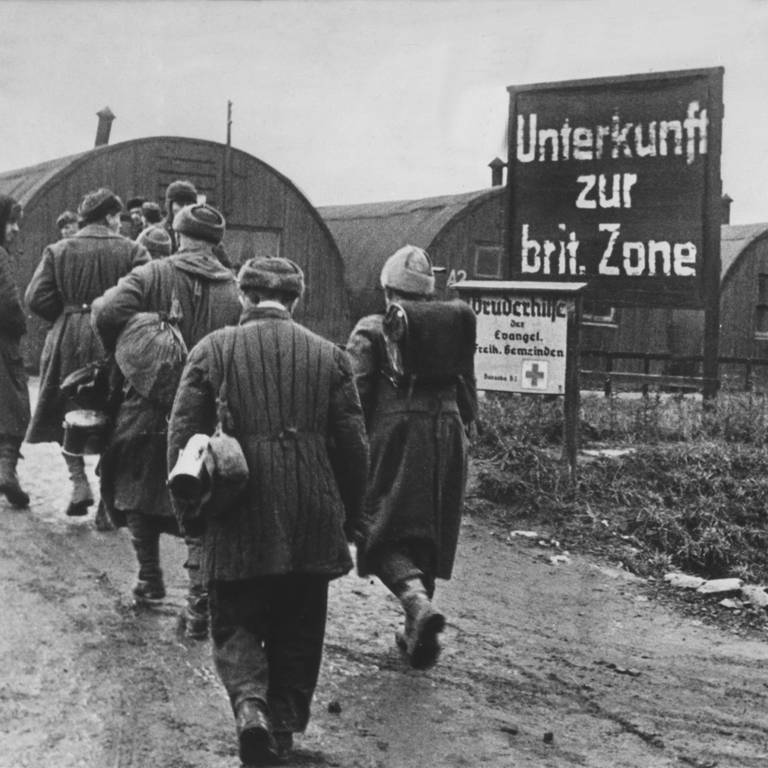 Heimkehrer gehen im Lager Friedland auf die als Notunterkünfte dienenden Nissenhütten zu (Archivfoto von 1946). Am 26. September 1945 eröffnete die britische Armee in dem Ort Friedland bei Göttingen ein Auffanglager.