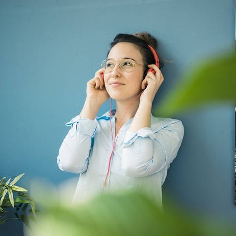 Das Bild zeigt eine junge Frau mit Kopfhörern (Foto: IMAGO, imago images/Westend61)