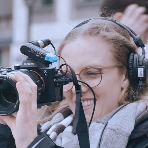 Mediengestalterin beim Außendreh mit einer Kamera