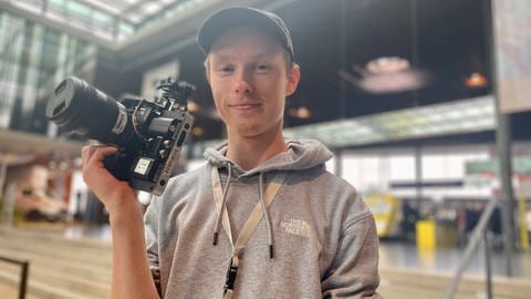 SWR Mediengestalter Azubi Leifur Seibt steht mit einer Kamera in der Hand auf der Stuttgarter Messe (Foto: SWR)