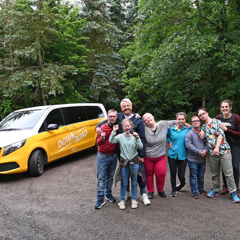 Die Reisegruppe steht vor ihrem Tourbus im Wald an der Geierlaybrücke (Foto: SWR, SEO Entertainment/Ben Pakalski)