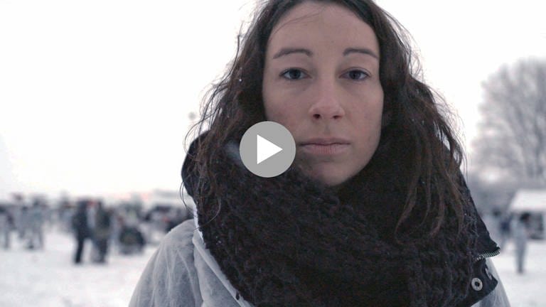 Journalistin und Bloggerin Johanna Maria Knothe ist im Vordergrund des Bildes. Es ist kalt, sie trägt einen dicken schwarzen Schal und hat vereinzelt Schneeflocken im langen dunklen Haar. im Hintergrund sind verschwommen Menschen zu erkennen.