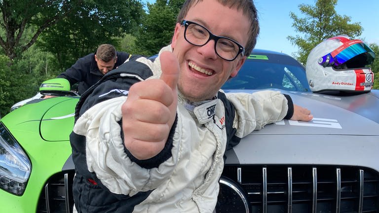 Patrick in Rennfahrermontur vor einem Boliden am Nürburgring