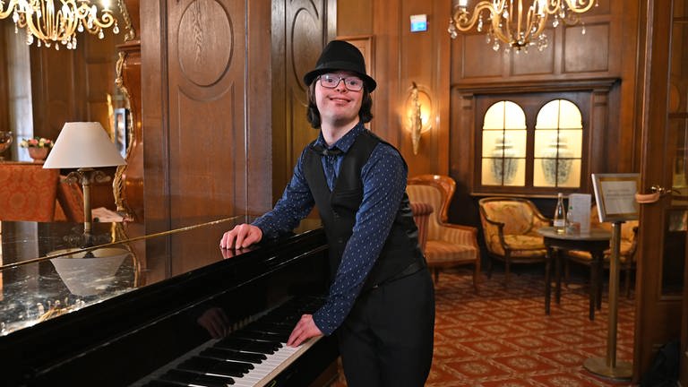 Julius in seinem Gala-Outfit am Klavier im Foyer eines Luxushotels in Baden-Baden. (Foto: SWR, SEO Entertainment/Ben Pakalski)