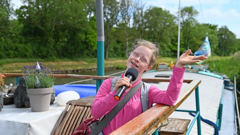 Rosalie ist auf dem Deck des Hausbootes und singt in ihr Mikrofon (Foto: SWR, SEO Entertainment/Ben Pakalski)