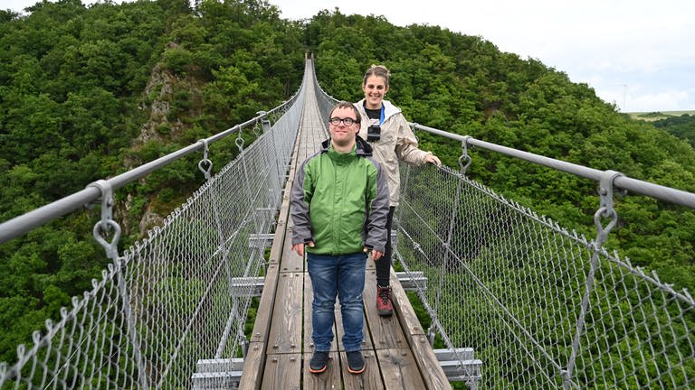 Nicole und Patrick laufen über die Geierlaybrücke, im Hintergrund dichter Wald (Foto: SWR, SEO Entertainment/Ben Pakalski)