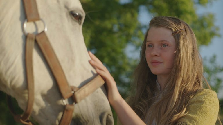 Jane (Aurelia Ott) streichelt das Pferd Wellington.