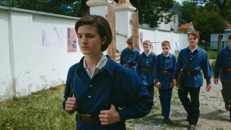 Rudolf (Cooper Dillon, li.) läuft mit traurigem Blick davon, im Hintergrund laufen fünf Jungen.