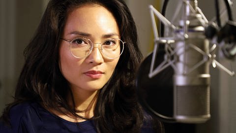 Porträtfoto der Schauspielerin Mai Duong Kieu hinter einem Mikrofon. Sie spielt im Hörspiel „Atlas“ die Rolle der Tochter. © SWRMDROlaf Parusel (Foto: SWR, MDR/Olaf Parusel)