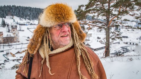 Der weltbekannte Interpret und Musiker Klaus Burger steht mit Fellmütze in der verschneiten Landschaft des Urals (Foto: SWR, Bildschön Film/Igor Kataev)