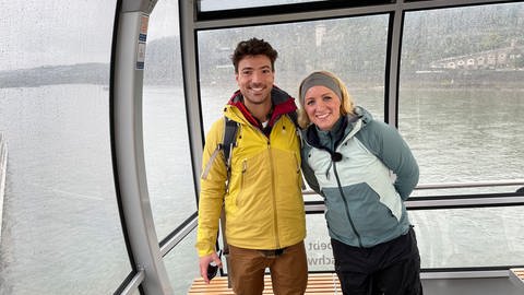 Das "Expedition in die Heimat"-Duo Ramon Babazadeh und Anna Lena Dörr sind nach 800 Kilometer Radtour entlang des Rheins am Ziel in Koblenz. Zusammen in der Seilbahn über dem Rhein. (Foto: SWR, Rolf Stephan)