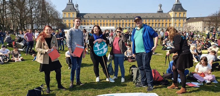 Mitglieder der katholischen Landjugendbewegung stehen bei einer "Fridays for Future"-Demo in Bonn im Kreis um ein Transparent des KLJB herum, das auf der Wiese liegt. Die jungen Katholikinnen und Katholiken setzen sich für mehr Klimaschutz ein. (Foto: SWR)