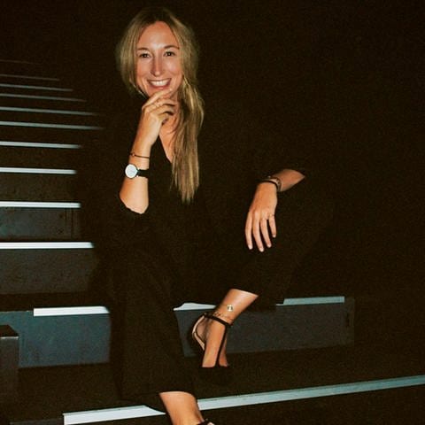 Marieke Reimann sitzt auf der Treppe in einem schwarzen Hosenanzug (Foto: SWR, Ralf Obergfell)