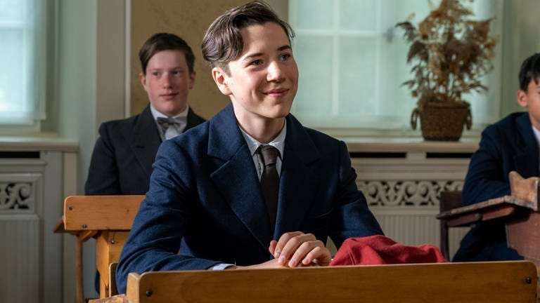 (v.l.n.r.): Herbert (Arthur Gropp) sitz im Klassenzimmer vor einem Holztisch.Im Hintergrund sitzt noch ein Junge (Foto: SWR, Steffen Junghans)