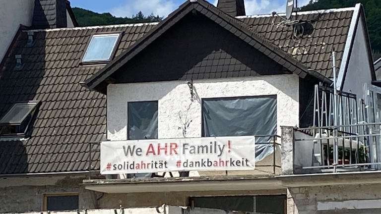 "We AHR Family" steht auf einem Transparent am Balkon eines sich im Aufbau befindenen Hauses (Foto: SWR, Dorothee Eisinger)