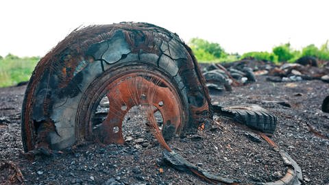 Ein alter, verbrannter Reifen inmitten eines abgebrannten Müllbergs aus Altreifen.  (Foto: SWR)