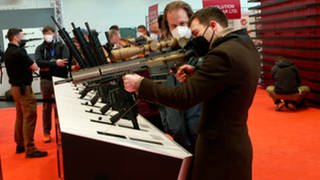Menschen testen Schusswaffen an einem Ausstellungsstand