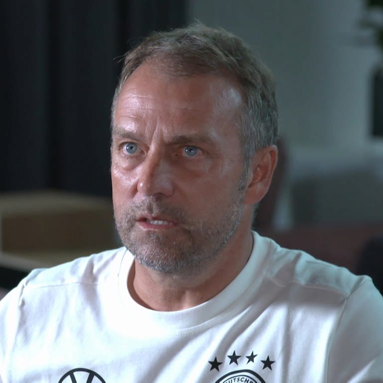 Das Bild zeigt Bundestrainer Hansi Flick im Interview. Er trägt das Trikot der deutschen Nationalmannschaft. 