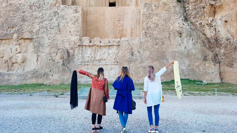 Drei Frauen im Iran protestieren gegen die Kopftuchpflicht, zwei davon halten ihr Kopftuch in der Hand