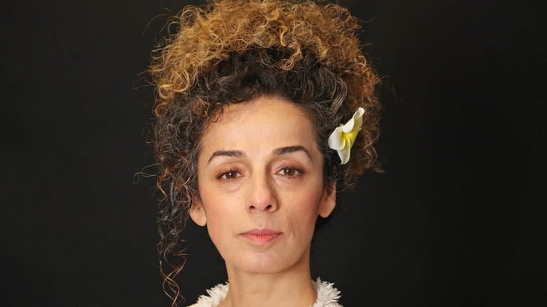 Die Frauenrechtlerin und Aktivistin Masih Aline, vor einem schwarzen Hintergrund mit einre Blume im Haar