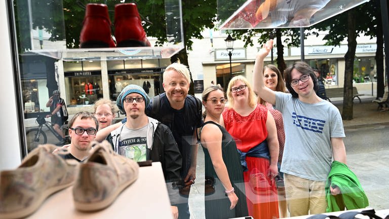 Die Gruppe schaut durch eine große Fensterscheibe eines Schuhgeschäfts in der Baden-Badener Fußgängerzone