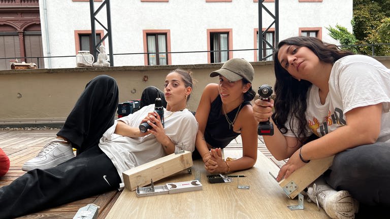Aslı Kaymaz, Aysu Yilmaz und Selin Dogan liegen auf ihrem Balkon mit jeder menge Werkzeug um sie herum