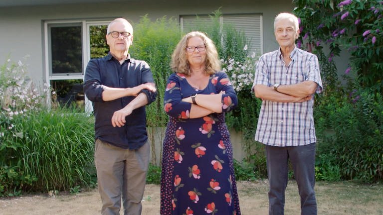 Simone Carstens, Walter Peter und Jesco von Puttkamer stehen in einem Garten