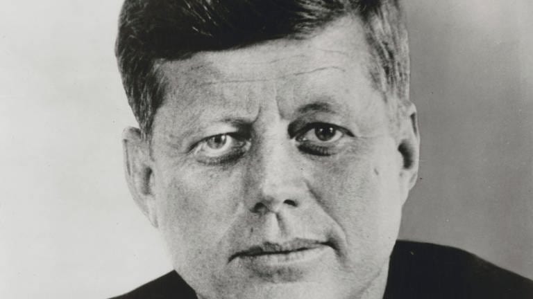 President John F. Kennedy lächelt in die Kamera (schwarz-weiß Bild)