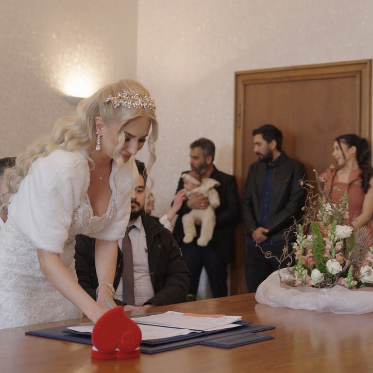 Eine Braut unterschreibt die Heiratsurkunde auf dem Standesamt.