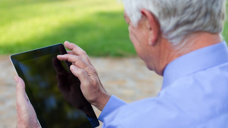 Ein älterer Mann, der über ein Tablet wischt (Foto: Getty Images)