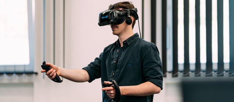 Sebastian Demuth beim Testen eines digitalen Produktes des SWR X Lab, er ist mit einem VR-Headset und zwei Controllern ausgestattet. (Foto: Christopher Müller)