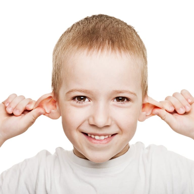 Junge zieht sich an beiden Ohren und lacht: Er hat es wohl faustdick hinter den Ohren (Foto: Colourbox)