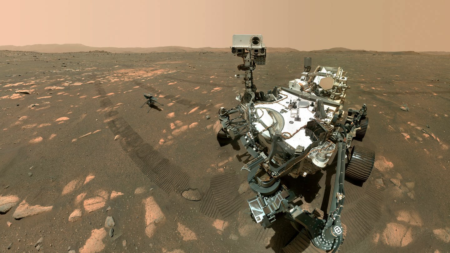 Mars-Rover Perseverance im Vordergrund und den Ingenuity-Hubschrauber etwa 3,9 Meter dahinter. Dieses zusammengesetzte Bild wurde von der WASTON-Kamera am Roboterarm des Rovers aufgenommen. (NASA-Bild vom 6. April 2021) (Foto: picture-alliance / Reportdienste, picture alliance / ASSOCIATED PRESS | Uncredited)