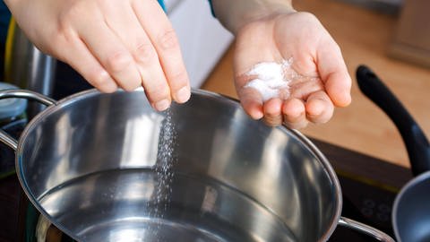 Eine Frau gibt Salz in einen Topf mit Wasser: Kocht gesalzenes Wasser schneller? (Foto: imago images, IMAGO / Panthermedia)