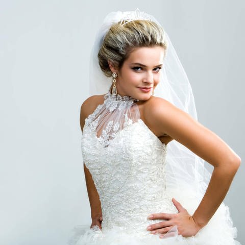 Braut posiert im weißen Kleid: Ein teures weißes Brautleid kann Luxus und Statussymbol sein