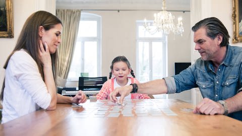 Kind und Eltern spielen gemeisam Memory: Ist Konzentrationsfähigkeit angeboren? (Foto: IMAGO, imago/Westend61)